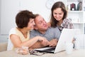 Daughter and parents searching documents on laptop