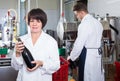 Female employee showing wine bottle at sparkling wine factory Royalty Free Stock Photo