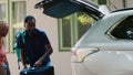 Positive african american couple putting voyage luggage inside car trunk Royalty Free Stock Photo