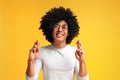 Positive african-american guy crossing fingers, making wish