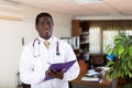 Positive african american male doctor writes important notes on a folder of documents