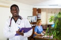 Positive african american male doctor writes important notes on a folder of documents