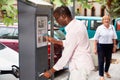 Positive African American man buying ticket for street parking in modern parking meter Royalty Free Stock Photo