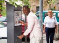 Positive African American man buying ticket for street parking in modern parking meter Royalty Free Stock Photo