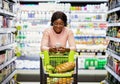 Positive African American woman checking grocery list on smartphone while shopping for food at supermarket