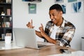 Positive african man gesturing while having video call via laptop at home Royalty Free Stock Photo