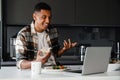 Positive african man having video call via laptop while having lunch at home Royalty Free Stock Photo