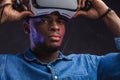 Positive african man taking off his VR glasses from his head on black background Royalty Free Stock Photo