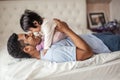 Positive Afro man touching his daughter`s nose with his nise