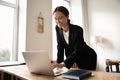 Positive ambitious young business woman working at laptop