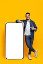 Positive arab guy with huge smartphone with blank screen