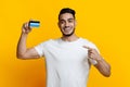 Positive arab guy recommending credit card, yellow background