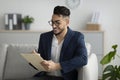 Positive arab male psychologist writing in clipboard, having session with client, sitting on couch in office and smiling Royalty Free Stock Photo