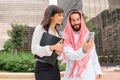 Arab man sharing data on cellphone with businesswoman