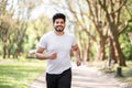 Positive arabian man in active outfit jogging at summer park