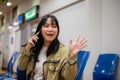 A positive Asian female traveler is calling her friend while waiting her friend at the airport Royalty Free Stock Photo