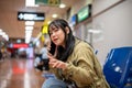 A positive Asian female traveler is talking on the phone while waiting her friend at the airport Royalty Free Stock Photo