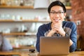 Positive asian male in glasses with laptop