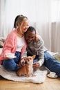 Positive asian woman with coffee hugging african american boyfriend near pet in bedroom Royalty Free Stock Photo