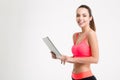 Positive attractive young fitness woman holding tablet