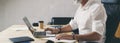 Positive bearded businessman using mobile laptop computer while sitting at wooden table at modern coworking place. Wide Royalty Free Stock Photo