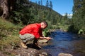 Positive bearded hiker washing face in mountain river