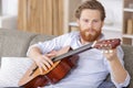 positive bearded man playing guitar