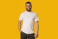 Positive bearded man posing over yellow background