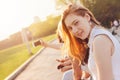 Positive beautiful happy red haired girl with friends on city street background, summer sunset time Royalty Free Stock Photo