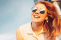 Positive beautiful happy red haired girl in the mirror sunglasses on blue sky background, summer sunset time Royalty Free Stock Photo