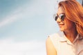 Positive beautiful happy red haired girl in the mirror sunglasses on blue sky background, summer sunset time Royalty Free Stock Photo