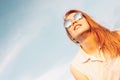 Positive beautiful happy red haired girl in the mirror sunglasses on blue sky background, summer sunset time Royalty Free Stock Photo