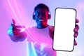 Positive black guy pointing at cell phone, using wireless headphones Royalty Free Stock Photo