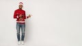 Positive black guy in Santa hat pointing at copy space