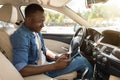 Positive black guy using digital tablet while driving car