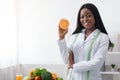 Positive black lady nutritionist holding orange half Royalty Free Stock Photo