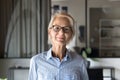 Positive blonde elder businesswoman in stylish glasses standing in office Royalty Free Stock Photo