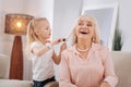 Positive blonde girl brushing her grandmothers hair
