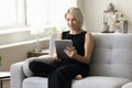 Positive blonde mature woman using online application on tablet Royalty Free Stock Photo