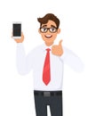 Positive business man showing new brand, latest smartphone. Man holding cell, mobile phone in hand and gesturing/making thumbs up. Royalty Free Stock Photo