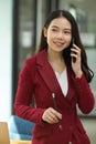 Positive business woman in red suit talking on modern smart mobile phone Royalty Free Stock Photo