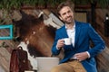 Positive businessman holding a coffee cup, fixing his jacket