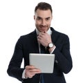 Positive businessman holding tablet and hand on chin Royalty Free Stock Photo