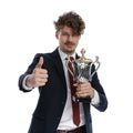 Positive businessman holding trophy and giving thumbs up Royalty Free Stock Photo