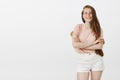 Positive and carefree attractive female student in pink t-shirt and shirts, holding hands crossed on chest in confident Royalty Free Stock Photo