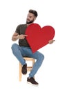Positive casual man pointing and holding a heart