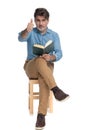 Positive casual man reading a book and giving thumbs up Royalty Free Stock Photo