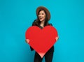 Positive casual woman holding heart shape and laughing