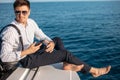 Man in sunglasses and trendy clothes sailing on motor boat