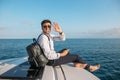 Man in sunglasses and trendy clothes sailing on motor boat